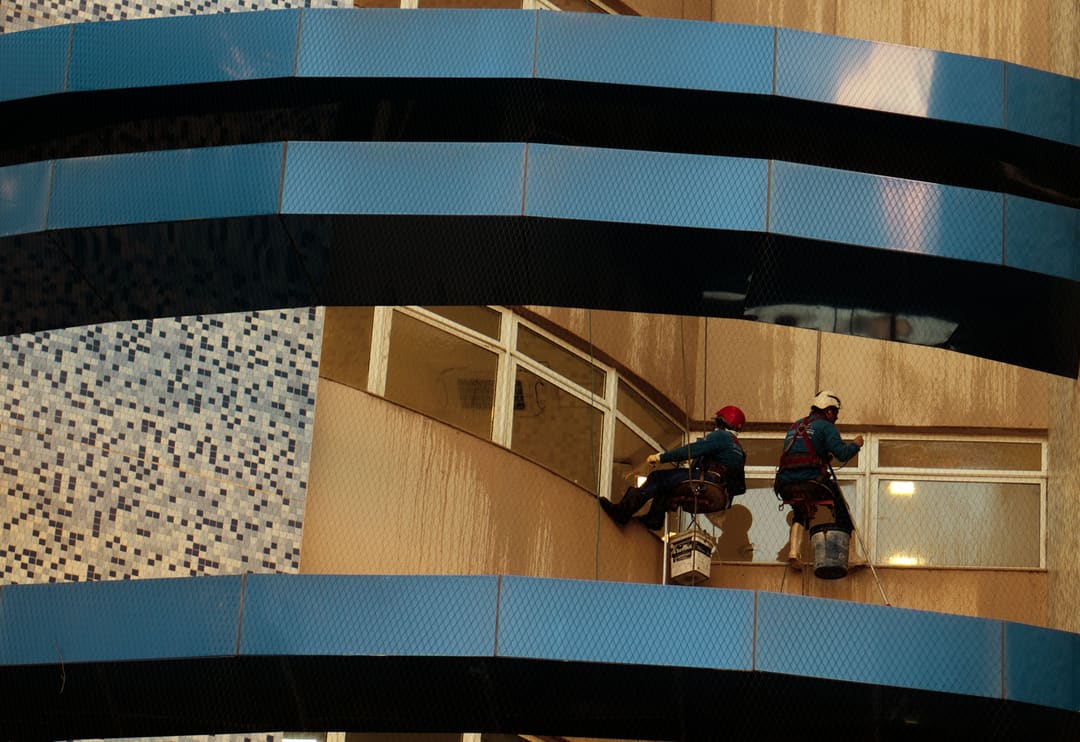 Dois profissionais em acesso por corda trabalhando na fachada de um edifício em São Paulo