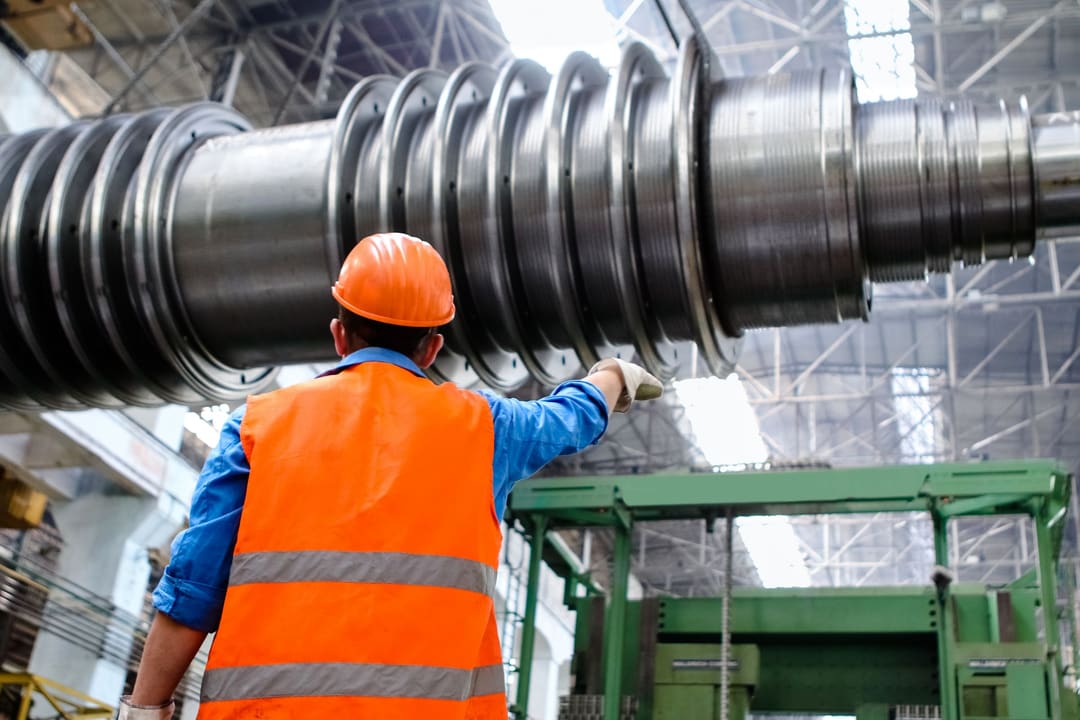 Técnico de segurança com capacete e colete refletivo inspecionando o rotor de uma turbina industrial
