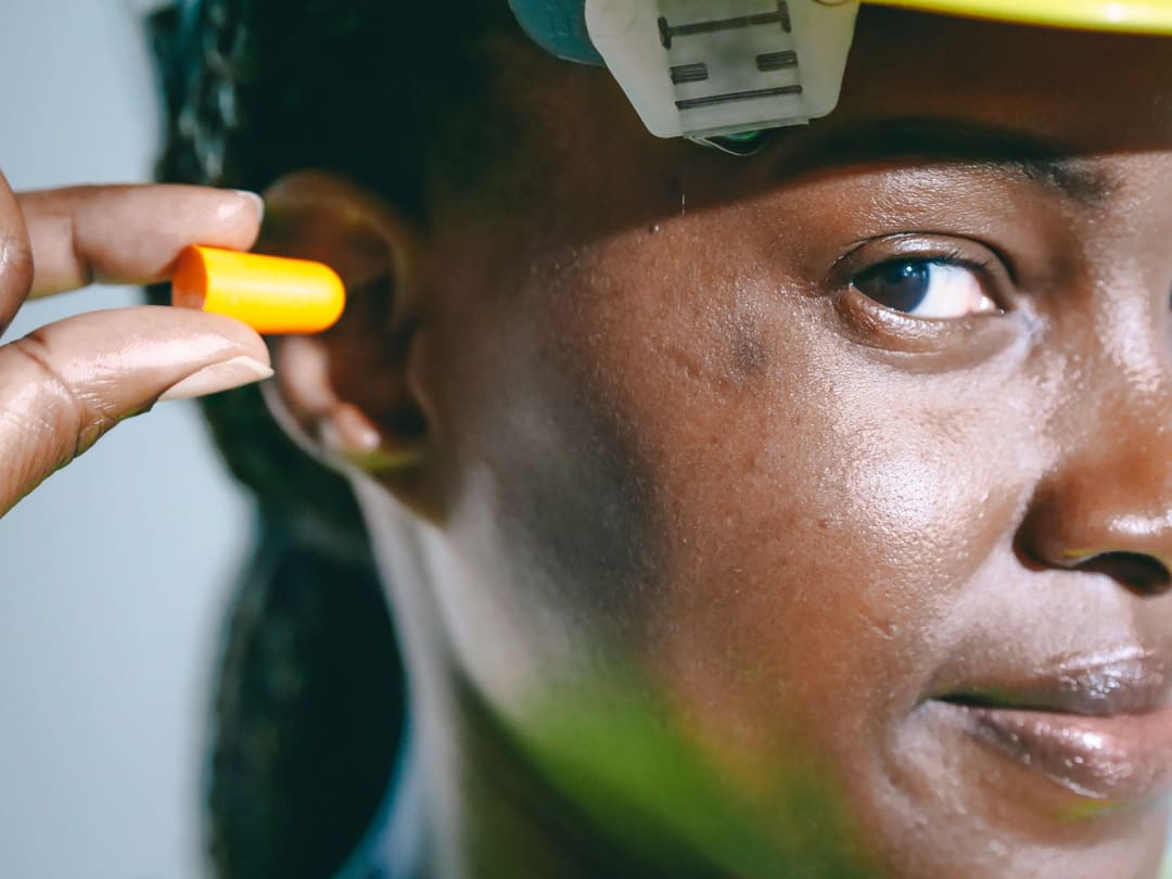 Profissional com capacete colocando protetor auricular de inserção